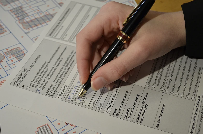 Eine Hand füllt das Formular Vorklärung Altlasten aus