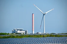 Eine Windkraftanlage steht hinter einem Photovoltaikanlage und verdeutlicht die Bedeutung regenerativer Energiegewinnung für die Regionalwirtschaft.