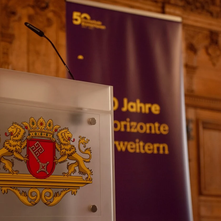 Ein Pult mit Bremer Wappen steht in der oberen Rathaushalle vor einem Banner der Hochschule Bremerhaven