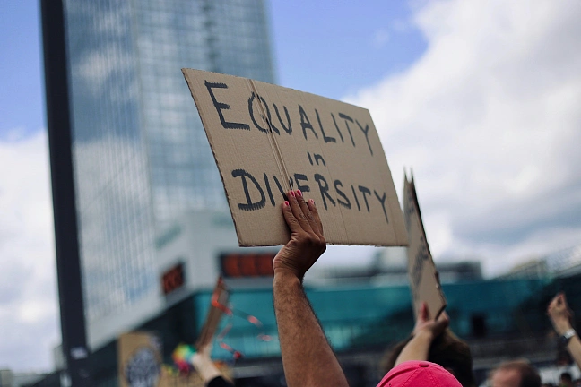 Ein Mensch hält ein Schild mit der Aufschrift Equality in Diversity in die Luft